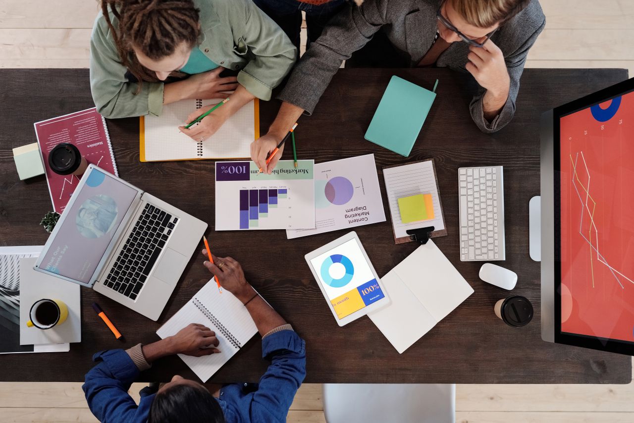who-we-are Overhead view of a diverse team collaborating on a project in a modern office setting.