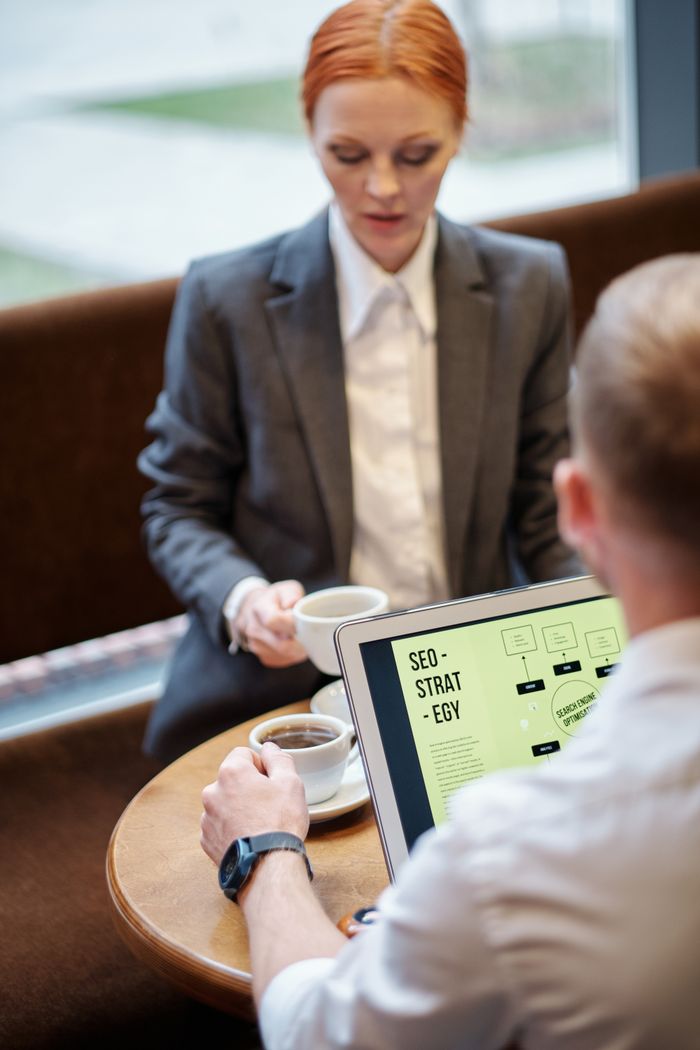 journey Professional meeting in a café with a laptop showcasing an SEO strategy. Ideal for business concepts.